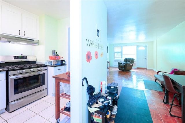 kitchen with stainless steel gas range oven, white cabinets, and light tile patterned flooring