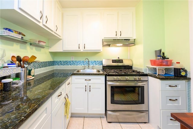 kitchen with white cabinetry, sink, stainless steel range with gas cooktop, dark stone counters, and light tile patterned floors