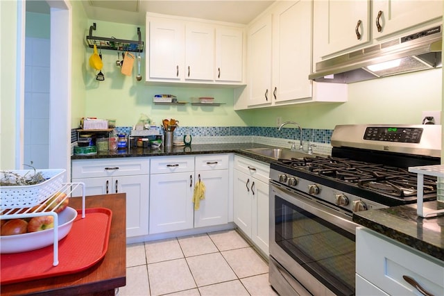 kitchen featuring dark stone counters, sink, light tile patterned floors, white cabinetry, and stainless steel range with gas stovetop