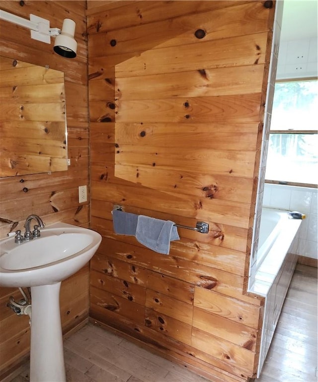 bathroom with a washtub, wood-type flooring, and wood walls