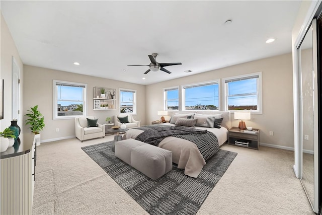 bedroom with multiple windows, ceiling fan, and light carpet