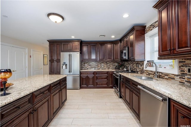 kitchen featuring backsplash, sink, light stone countertops, and stainless steel appliances