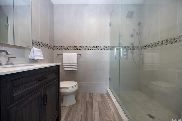 bathroom featuring an enclosed shower, vanity, toilet, and tile walls