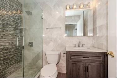 bathroom with vanity, toilet, walk in shower, and tile walls