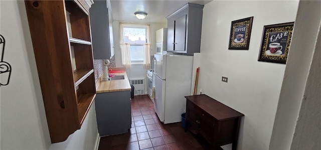 laundry room with dark tile patterned flooring, sink, and radiator