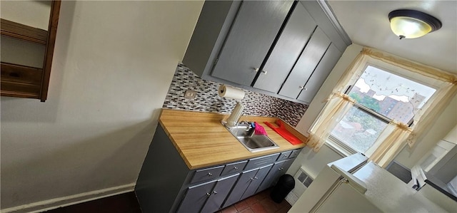 kitchen with gray cabinets, sink, and tasteful backsplash