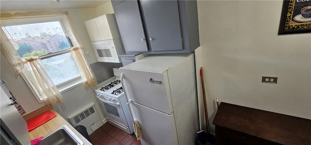 kitchen featuring white appliances, dark tile patterned floors, gray cabinetry, and sink