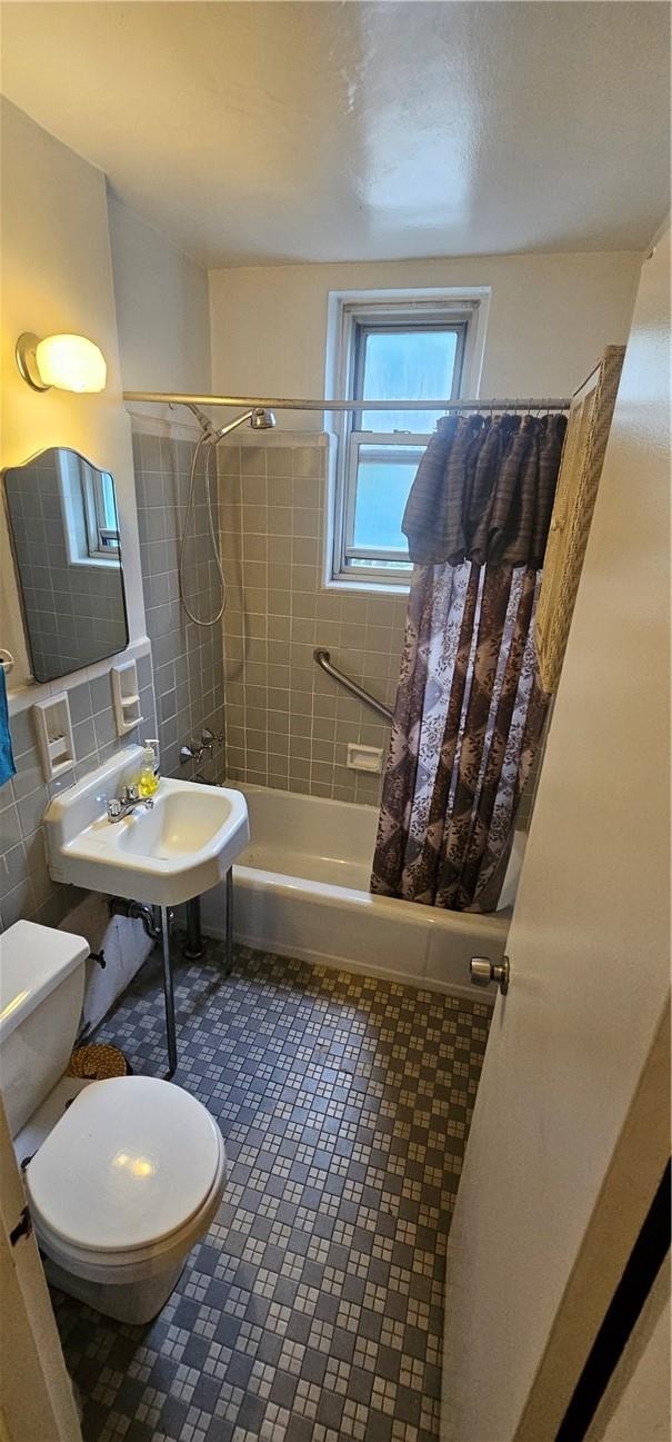 full bathroom featuring shower / bath combo, backsplash, sink, toilet, and tile walls