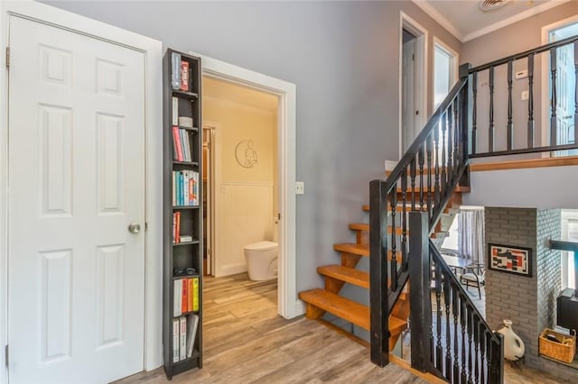 stairs with crown molding and hardwood / wood-style flooring