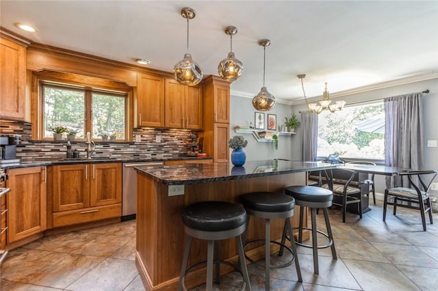 kitchen with decorative backsplash, stainless steel dishwasher, sink, a chandelier, and a center island