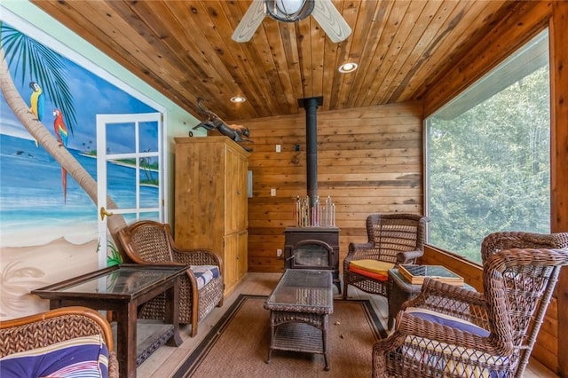 sitting room featuring a healthy amount of sunlight, a wood stove, and wooden walls