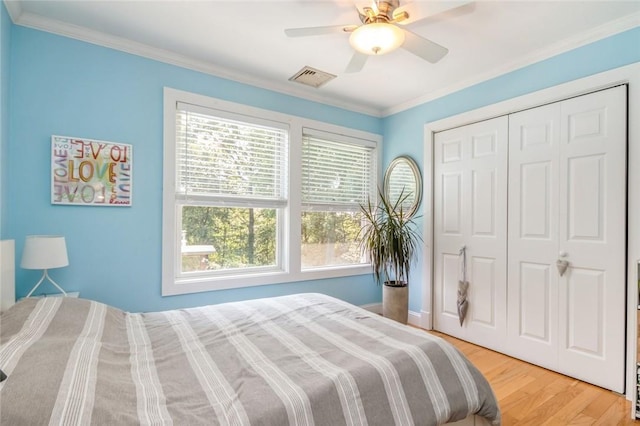 bedroom with hardwood / wood-style flooring, ceiling fan, crown molding, and a closet