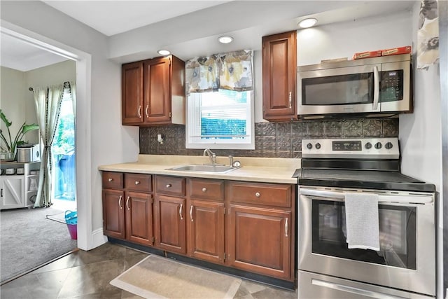 kitchen with tasteful backsplash, a wealth of natural light, sink, and appliances with stainless steel finishes