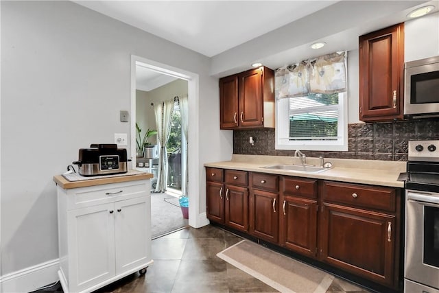 kitchen with dark tile patterned flooring, decorative backsplash, sink, and appliances with stainless steel finishes