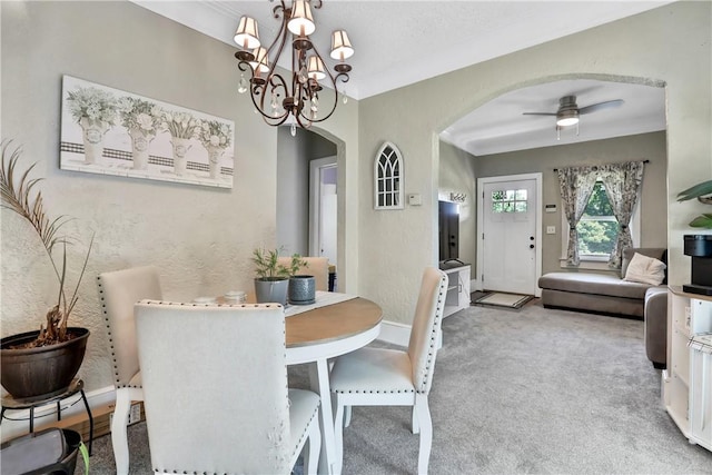 dining room with carpet flooring, ceiling fan with notable chandelier, and ornamental molding