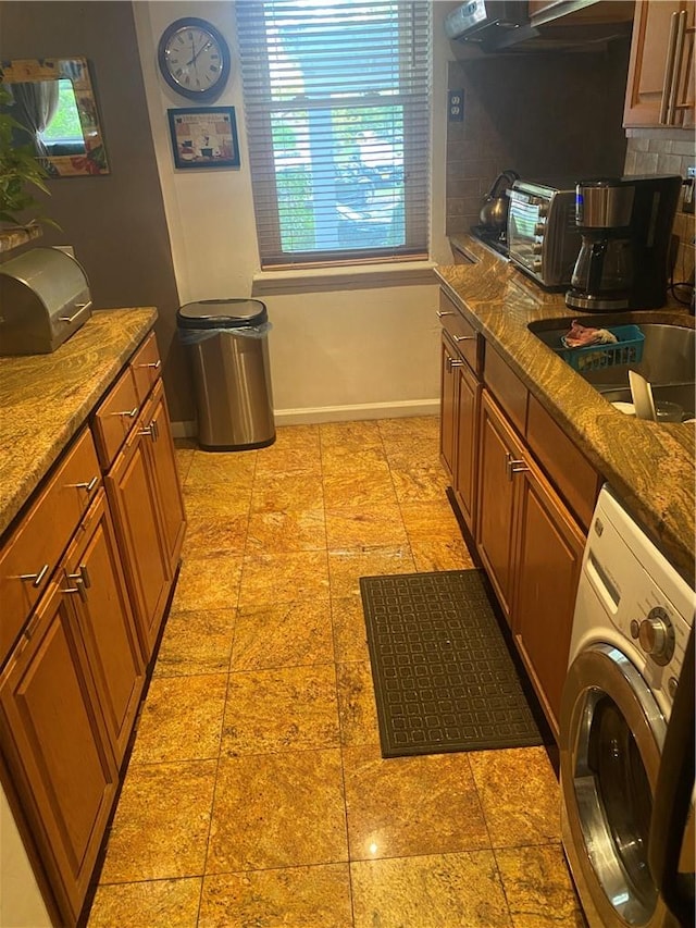 kitchen with backsplash, range hood, stone countertops, and washer / dryer