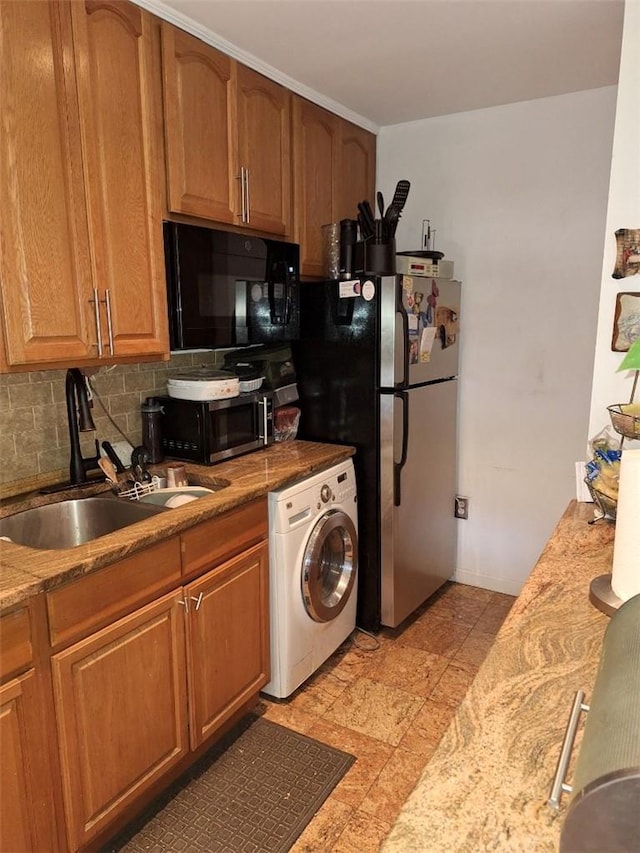 kitchen with backsplash, sink, light stone countertops, appliances with stainless steel finishes, and washer / clothes dryer