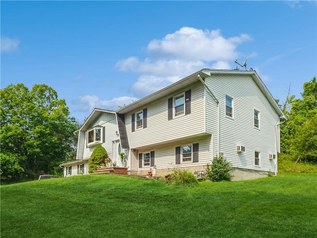 view of front of property featuring a wall mounted AC and a front lawn