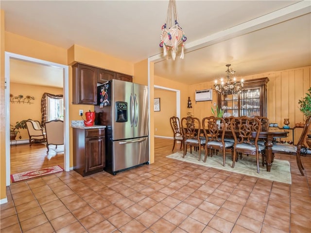 kitchen featuring stainless steel refrigerator with ice dispenser, dark brown cabinets, a wall unit AC, decorative light fixtures, and a notable chandelier