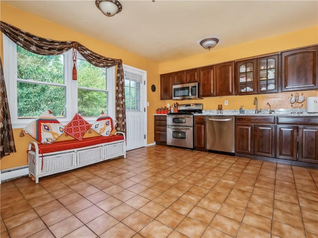 kitchen featuring dark brown cabinets, stainless steel appliances, baseboard heating, sink, and light tile patterned floors