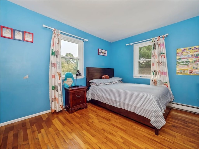 bedroom with light hardwood / wood-style floors and a baseboard radiator