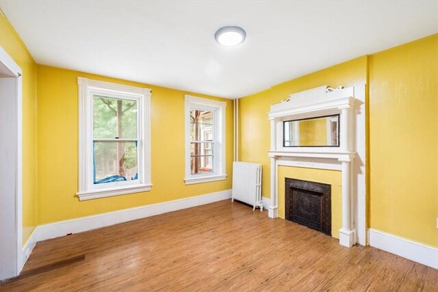 unfurnished living room featuring light wood-type flooring and radiator heating unit