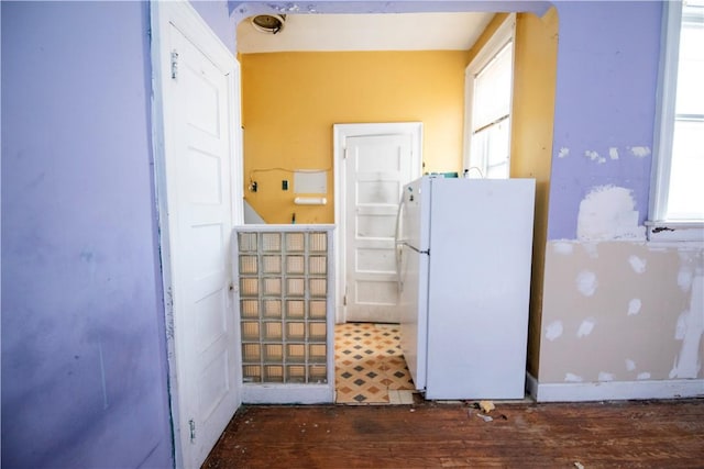 interior space with dark wood-type flooring, white fridge, and a healthy amount of sunlight