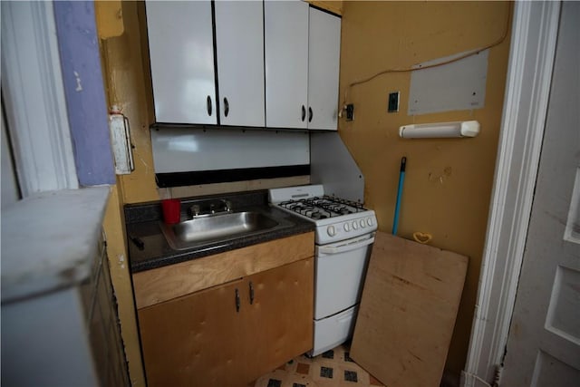 kitchen featuring white gas stove, white cabinets, and sink