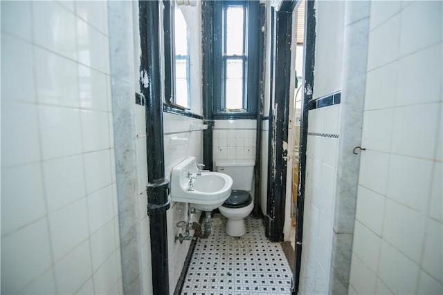 bathroom with toilet, tile walls, and sink