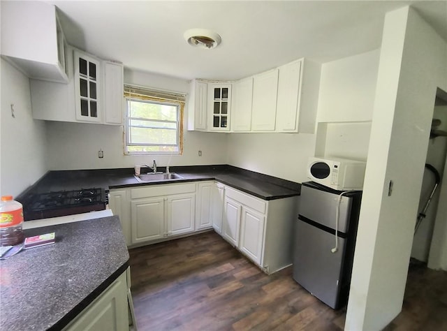 kitchen featuring black range oven, sink, dark hardwood / wood-style floors, white cabinetry, and stainless steel refrigerator