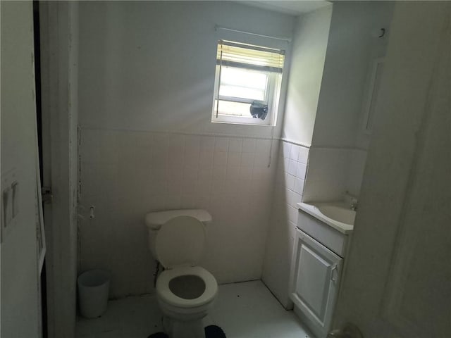 bathroom featuring vanity, toilet, and tile walls