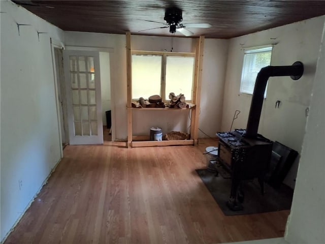 exercise room with a wood stove, ceiling fan, and hardwood / wood-style floors