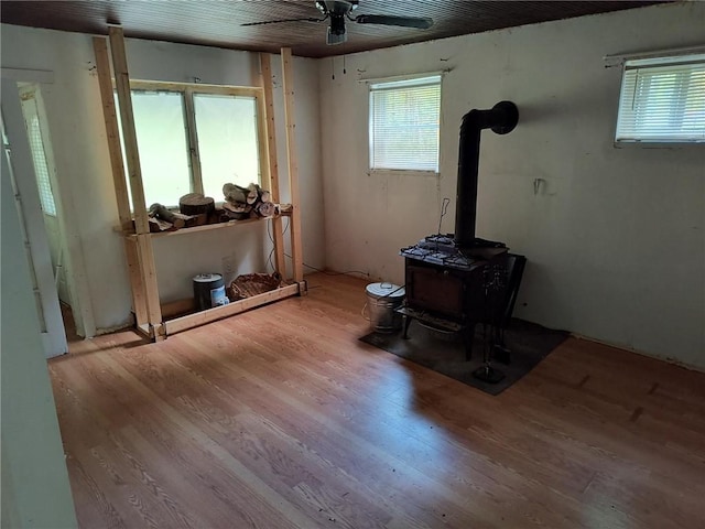 miscellaneous room with light wood-type flooring, a wood stove, and ceiling fan