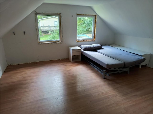 bedroom featuring light hardwood / wood-style floors, vaulted ceiling, and multiple windows