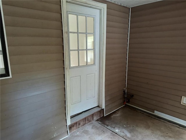 doorway with concrete flooring and wooden walls