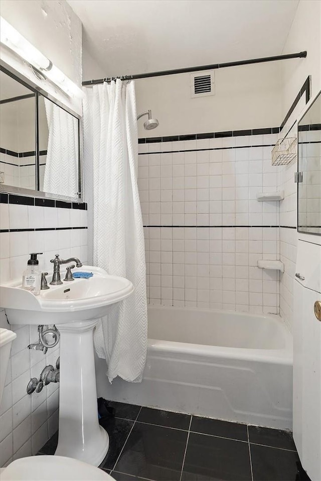 bathroom featuring backsplash, tile patterned floors, toilet, shower / tub combo with curtain, and tile walls