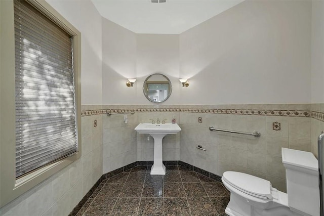 bathroom featuring tile walls and toilet