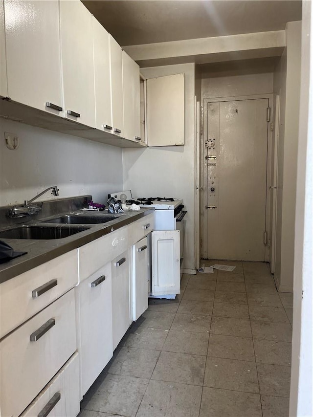 kitchen with white cabinets, light tile patterned floors, and sink