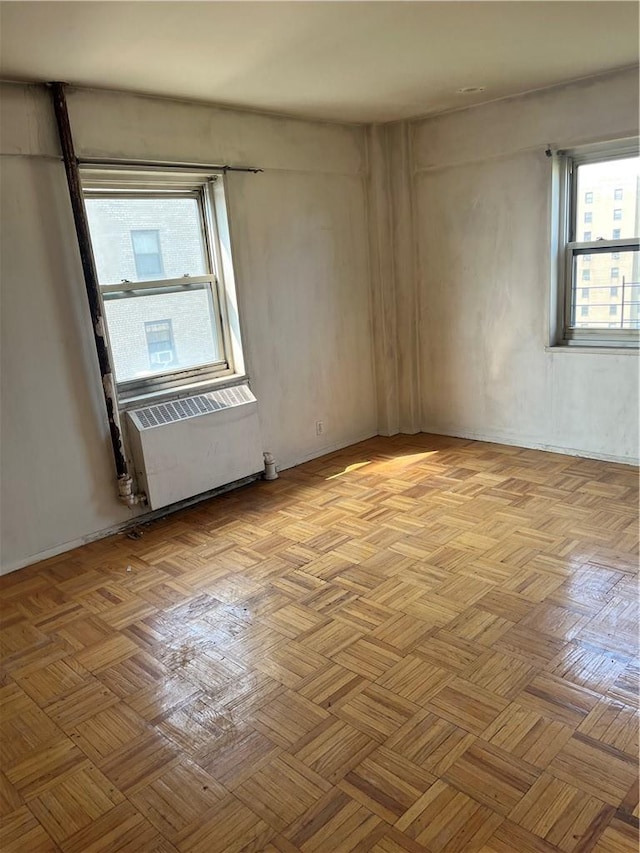 spare room with radiator, plenty of natural light, and light parquet floors