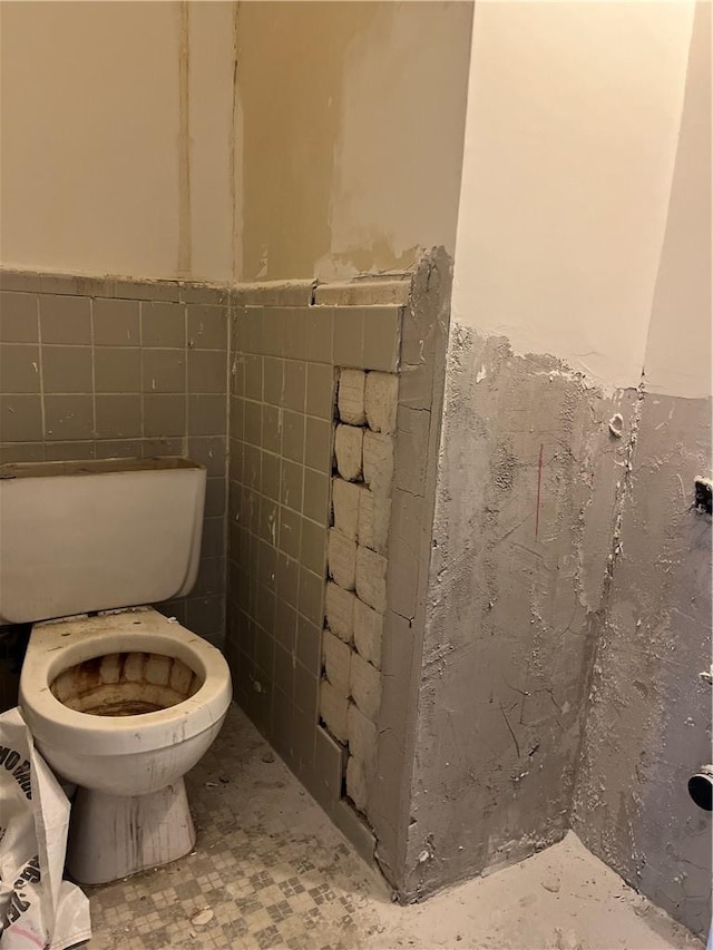 bathroom with toilet and tile walls