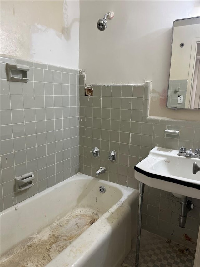 bathroom with a bathing tub, sink, tile walls, and water heater