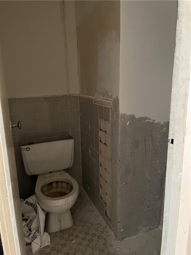 bathroom with toilet and tile walls