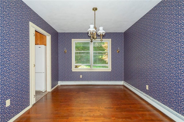 unfurnished dining area with a notable chandelier, dark wood-type flooring, and a baseboard heating unit