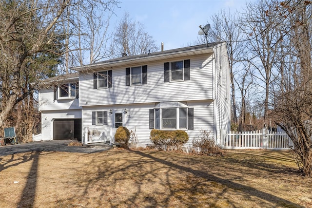 colonial house with a front lawn, driveway, an attached garage, and fence