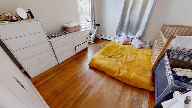 bedroom with hardwood / wood-style floors and a baseboard radiator