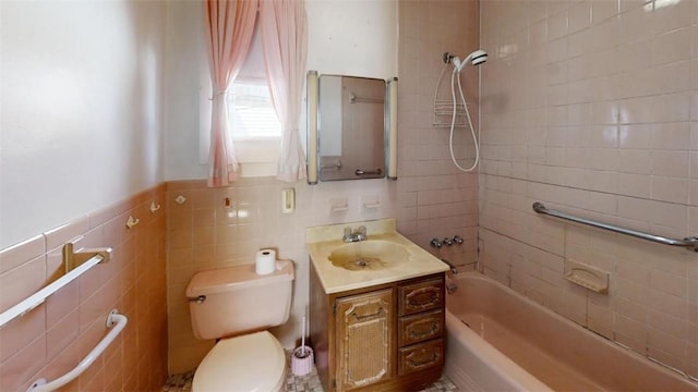 full bathroom featuring tiled shower / bath, vanity, tile walls, and toilet