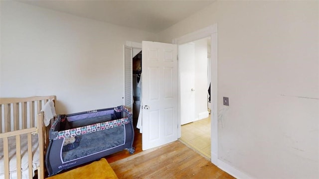 bedroom with wood-type flooring and a crib