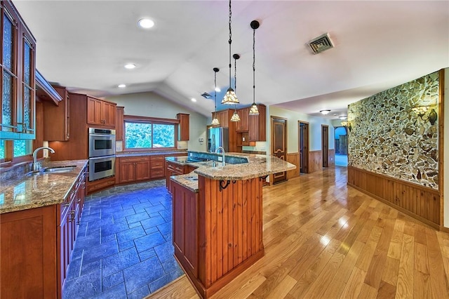 432 Black Forest Rd, Glen Spey, NY 12737 - kitchen featuring stainless steel double oven, a wainscoted wall, brown cabinetry, a kitchen bar, and lofted ceiling