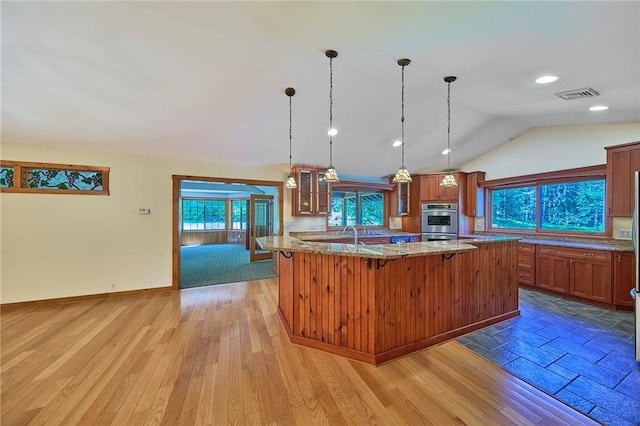 432 Black Forest Rd, Glen Spey, NY 12737 - kitchen featuring glass insert cabinets, light stone counters, lofted ceiling, brown cabinetry, and a breakfast bar
