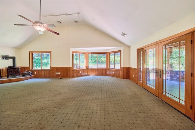 432 Black Forest Rd, Glen Spey, NY 12737 - unfurnished living room featuring a wood stove, wainscoting, track lighting, lofted ceiling, and a ceiling fan